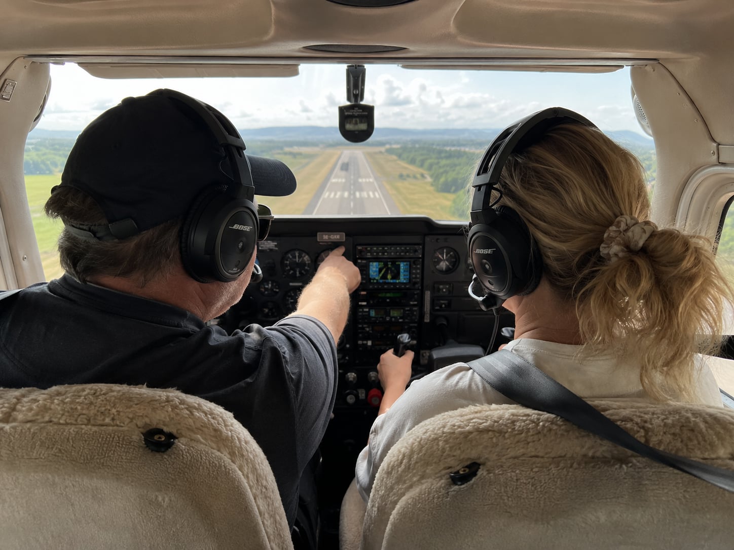 Vy från cockpit på final mot rullbana med två personer med headset